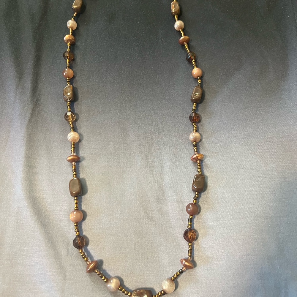 Long necklace, earthy tones.